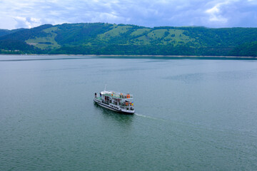 A ship full of tourists on the lake. Lake between mountains in Romania.