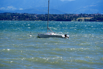 Lake Geneva on a sunny and windy summer day with sailing boat and European Alps in the background. Photo taken August 28th, 2021, Nyon, Switzerland.