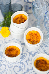 French dessert creme brulee with caramel crust in white baking molds on blue and white tablecloth 