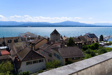 Fototapeta na wymiar Beautiful view over the old town of Nyon with Lake Geneva and European Alps in the background on a sunny summer day. Photo taken August 28th, 2021, Nyon, Switzerland.