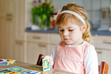 Adorable cute toddler girl playing picture card game. Happy healthy child training memory,...