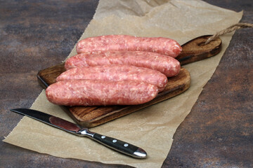 Grobe Bratwürste auf einem Küchenbrett.