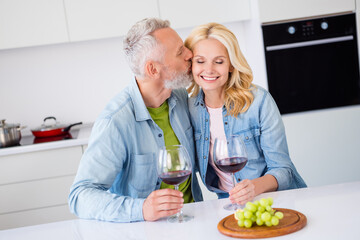 Photo of lovely cute smiling married couple spouses celebrate anniversary date drink wine husband kiss wife affectionate