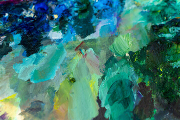 Blue turquoise oil paint close-up. Blurry multicolored background. The artist's professional paints are in selective focus. The concept of creativity, creative ideas, favorite hobby. Painting classes