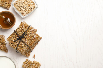 Delicious sweet kozinaki bars, honey and milk on white wooden table, flat lay. Space for text