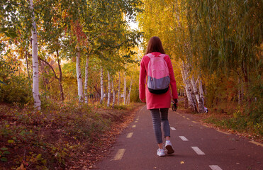 Fototapeta premium Faceless female traveler walking in park in autumn