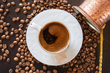 coffee beans in the background and a cup of frothy turkish coffee on top. Selective Focus.