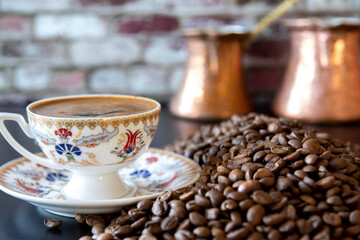 Turkish coffee over a cup of smoke. beans next to it and pots in the background. Selective Focus tulip pattern Cup. 