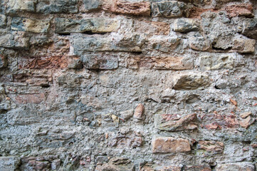 Grey white black red orange old vintage brick wall background. Rustic cemented brick house wall texture with grunge surface. Shabby Building Facade With Damaged Plaster