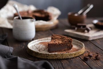 Chocolate cake on a wooden table. A piece of brownie on a brown background. Cocoa and chocolate pieces. Serving dessert.