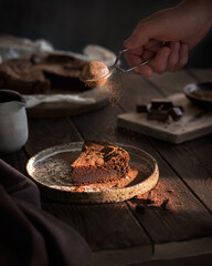 Chocolate cake on a wooden table. A piece of brownie on a brown background. Cocoa and chocolate...