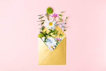 Golden envelope with beautiful spring garden flowers on pink background