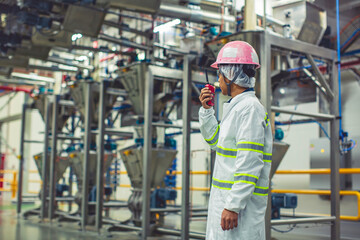 Male engineers  sound protection and uniform staff.Hand holding portable radio transceiver for communication work inspection process powder stainless steel tanks