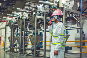 Male engineers  sound protection and uniform staff.Hand holding portable radio transceiver for communication work inspection process powder stainless steel tanks