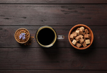 Glass cup of delicious chicory drink, granules, brown sugar and flower on wooden table, flat lay