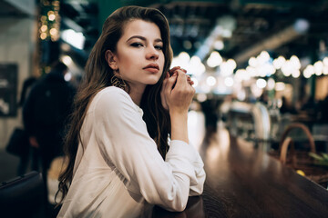 Half length portrait of young Caucaisan woman dressed in smart casual white shirt looking at camera during leisure pastime in shopping center, attractive female with natural beauty posing indoors