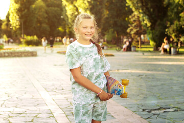 Cute smiling teenager girl with skateboard in the park on a summer sunny day having fun. Healthy lifestyle concept for teenagers and children on vacation