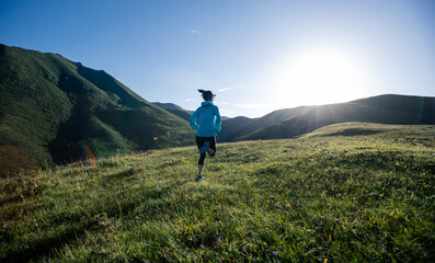 Obraz premium Young woman runner running at mountain top