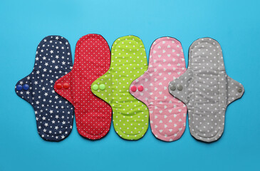 Many reusable cloth menstrual pads on light blue background, flat lay