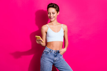Portrait of attractive cheerful girl using device gadget chatting isolated over bright pink magenta...