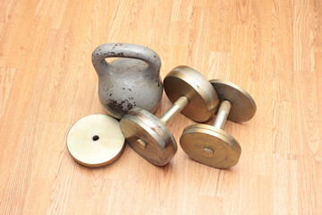 Heavy metal dumbbells and weights on wooden floor
