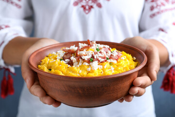 Woman holding bowl of banosh with brynza and pork cracklings, closeup. Traditional Ukrainian dish