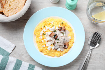 Tasty banosh served with brynza and mushrooms on light wooden table, flat lay. Traditional Ukrainian dish