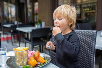 Preschool child, cute boy, eating fish and chips a restaurant, cozy atmosphere, local small...