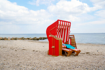 Traditional German roofed wicker beach chairs on the beach of Baltic Sea. Beach with red chairs on...