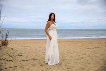 Fototapeta na wymiar Glückliche junge Frau im Hochzeitskleid am Meer 