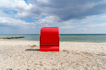 Traditional German roofed wicker beach chairs on the beach of Baltic Sea. Beach with red chairs on...