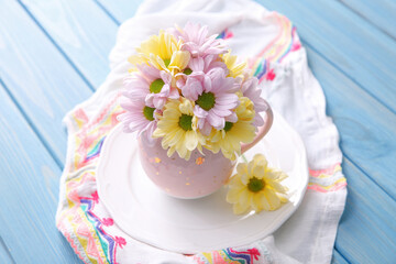 Fototapeta na wymiar Bouquet of beautiful flowers in cup on light blue wooden table