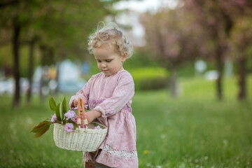 Beautiful toddler blond child, cute little girl in vintage rose dress, playing in the park springtime