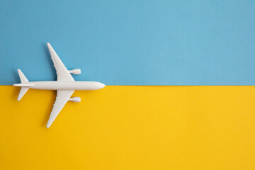 overhead lay flat of a white passenger aircraft on a bright blue and yellow background