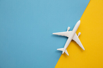 overhead lay flat of a white passenger aircraft on a bright blue and yellow background