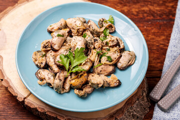 Peeled mussels in sauce on a dark wooden background.