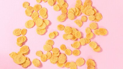 Cornflakes are scattered on a pink background. Background, space for the text.