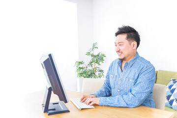 家でパソコンを使う男性