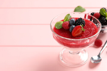 Delicious panna cotta with fruit coulis and fresh berries served on pink wooden table. Space for text