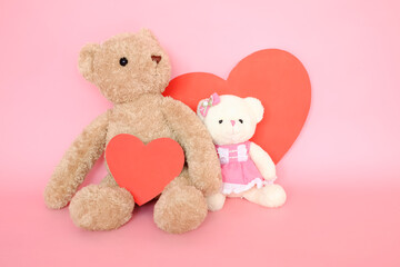 couple teddy bears with red heart card on pink background
