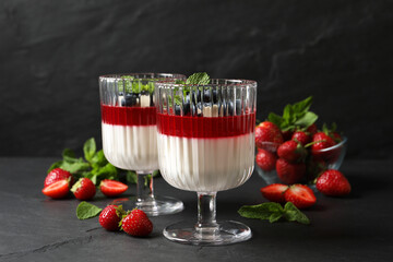 Delicious panna cotta with fruit coulis and fresh berries on dark grey table