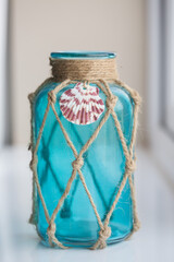Decorative light blue glass jar wimacrame knotting cord of twine and a seashell ornament