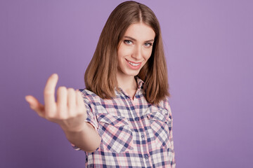 Portrait of smiling positive girl making beckoning gesture with finger inviting isolated over...