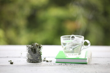 Pandan tea and leaves piles in small glass pitcher with green notebook