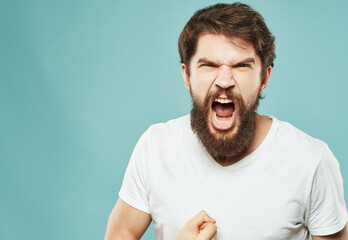 disgruntled man in white t-shirt anger scream emotion blue background