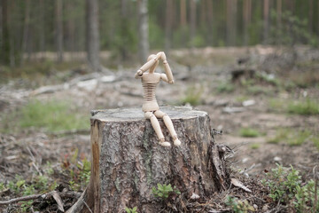 Wooden man on a stump in the forest, deforestation concept.