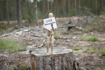 Wooden man on a stump in the forest, deforestation concept.
