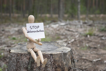 Wooden man on a stump in the forest, deforestation concept.