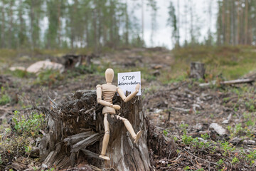 Wooden man on a stump in the forest, deforestation concept.