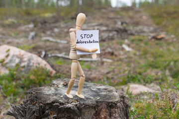 Wooden man on a stump in the forest, deforestation concept.